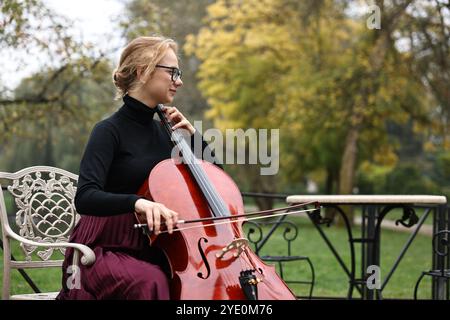 Belle jeune femme jouant du violoncelle dans le parc, espace pour le texte Banque D'Images