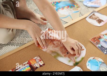 Petit garçon créant un tableau de vision avec différentes images et d'autres éléments sur le sol à l'intérieur, gros plan Banque D'Images