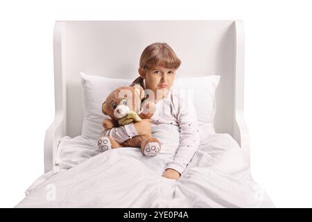 Fille triste assise dans le lit et tenant un ours en peluche Banque D'Images