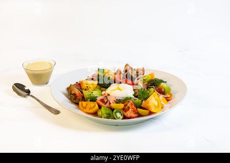 Tomates anciennes, salade de burrata fraîche dans un grand bol blanc avec vinaigrette sur le côté. Banque D'Images