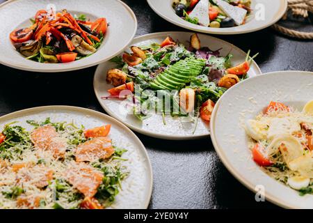 Salades gourmandes avec divers ingrédients dont avocat, feta, légumes grillés et saumon Banque D'Images