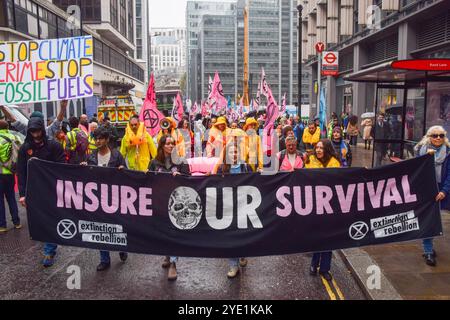 Londres, Royaume-Uni. 28 octobre 2024. Les activistes défilent avec la bannière « assurer notre survie » alors que extinction Rebellion commence trois jours de manifestations dans la City de Londres, le quartier financier de la capitale, appelant les compagnies d'assurance à cesser d'assurer les projets de combustibles fossiles. Crédit : SOPA images Limited/Alamy Live News Banque D'Images