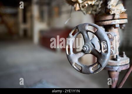 Vanne de style rétro pétrochimique chimique industrielle poussiéreuse gros plan avec accent sélectif sur le volant monté avec raccord à bride sur le tuyau, sortie o Banque D'Images