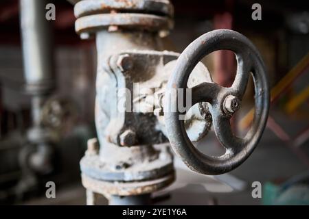 Vanne de style rétro pétrochimique chimique industrielle poussiéreuse gros plan avec accent sélectif sur le volant monté avec raccord à bride sur le tuyau, sortie o Banque D'Images