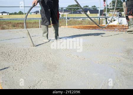 Ouvriers remplissant le sol du deuxième étage avec le béton, le noyau et le bâtiment de construction de coquille Banque D'Images