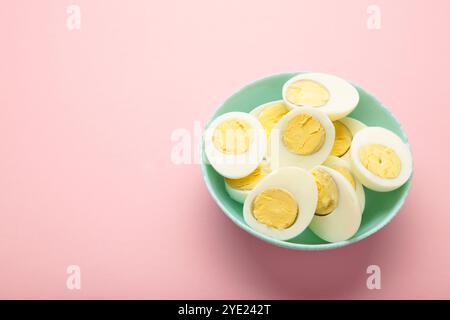 Oeuf dur coupé en deux avec jaune sur plaque sur fond rose. Vue de dessus. Banque D'Images