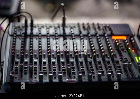 Gros plan d'une console de mixage audio avec faders et boutons en basse lumière Banque D'Images