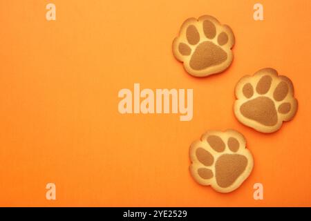 Cookies de patte de chat auto-faits sur fond orange. Vue de dessus Banque D'Images