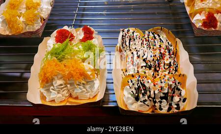 Crêpes croustillantes thaïlandaises version modifiée, fourrées de crème sucrée, sauce au chocolat, noix de coco râpée, lanières de jaunes d'œufs, vendues chez Thai Red Cros Banque D'Images