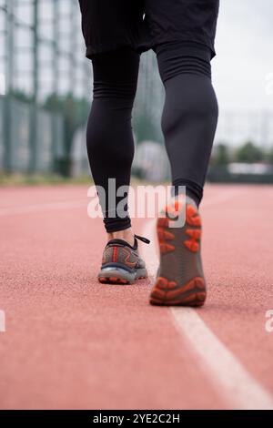 Les jambes de jogger concentrées dans des baskets confortables font la course sur piste dans un stade urbain Banque D'Images