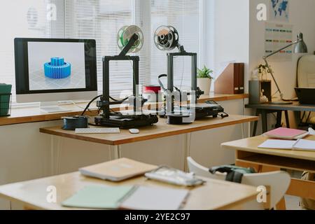 Espace de travail avec plusieurs imprimantes 3D créant activement des engrenages complexes. Lumière naturelle éclatante qui pénètre à travers les fenêtres mettant en valeur les technologies de pointe Banque D'Images