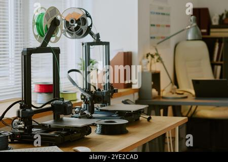 Doté de deux imprimantes avec bobines vertes et noires imprimant sur un bureau en bois dans un espace de bureau bien organisé avec divers gadgets et équipements visibles Banque D'Images