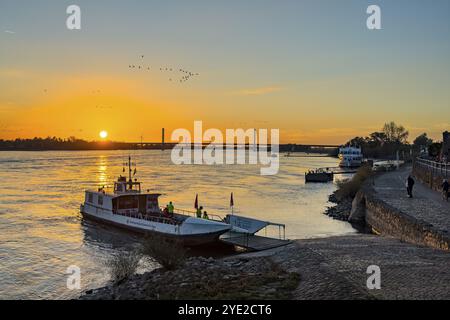Coucher de soleil sur le Rhin Rhin Bas Rhin, sur la gauche au premier plan petit ferry à passagers deux roues ferry Rees, sur la rampe de droite et la rive pavée, i Banque D'Images