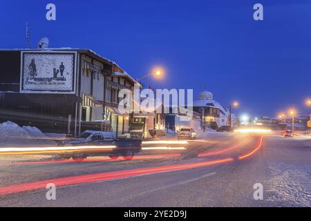 Route enneigée, ville, voitures, bâtiments, froid, neige, crépuscule, clair de lune, Arctique, peuplement inuit, Inuvik, Territoires du Nord-Ouest, Canada, Amérique du Nord Banque D'Images