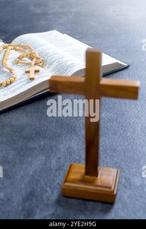 Croix de religion et livre ouvert de la Sainte Bible avec des perles de chapelet. Il est allongé sur la table. Symbole de foi et de culte en Dieu. Service religieux chrétien Banque D'Images