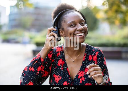 Jeune femme écoutant de la musique avec des écouteurs dans la ville Banque D'Images
