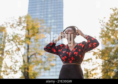 Jeune femme écoutant de la musique avec des écouteurs dans la ville Banque D'Images