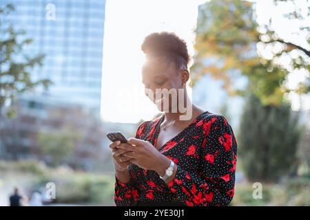Heureuse jeune femme utilisant le téléphone portable dans la ville Banque D'Images