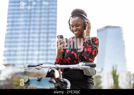 Portrait d'une jeune femme souriante avec son vélo dans la ville Banque D'Images