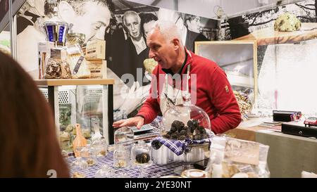 Au Festival de la truffe d'Alba, un vendeur enthousiaste présente les riches saveurs des truffes. Les visiteurs explorent les spécialités locales Banque D'Images