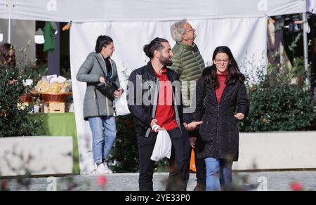 Deux personnes se promènent dans un marché animé à Alba, en Italie, tandis que d'autres parcourent divers stands de nourriture. Le cadre animé est rempli de bavardages Banque D'Images