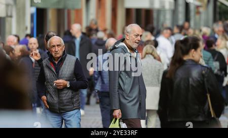 Des foules de gens se promènent dans une rue animée d'Alba, en Italie, avec des acheteurs qui s'engagent dans la conversation et apprécient l'atmosphère locale vibrante Banque D'Images