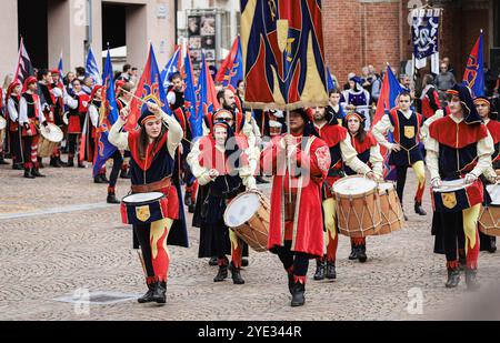 Dans les rues historiques d'Alba, en Italie, un défilé dynamique présente des artistes en costumes traditionnels jouant de la batterie et agitant des drapeaux Banque D'Images