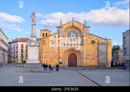 Avila, Espagne - 11 février 2023 : touristes sur la place près de la paroisse de l'apôtre Pierre, avec une façade en pierre de couleur orange. Banque D'Images