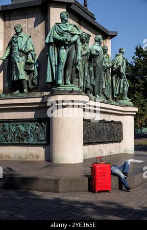 Un homme avec un chariot rouge se trouve à la statue équestre Empereur Friedrich Wilhem III, roi de Prusse au Heumarket, statues sur le piédestal, Cologn Banque D'Images