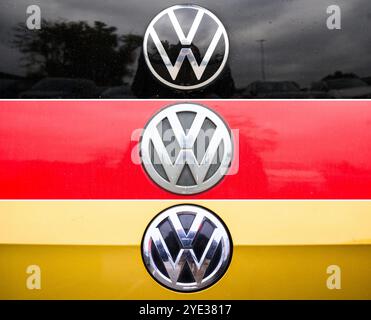 Wolfsburg, Allemagne. 29 octobre 2024. KOMBO - le logo VW sur un capot noir, rouge et or dans le style du drapeau allemand peut être vu dans un parking d'employés à l'usine principale de VW. VW et le comité d'entreprise luttent depuis des semaines contre d'éventuelles fermetures d'usines et licenciements. Selon le comité d'entreprise, les premiers plans concrets sont maintenant sur la table. Crédit : Julian Stratenschulte/dpa/Alamy Live News Banque D'Images