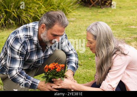 Couple mature plantant des fleurs ensemble dans le jardin, profitant de l'activité de plein air Banque D'Images