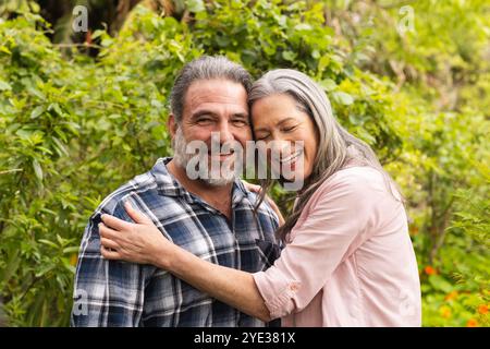 Heureux couple mature embrassant à l'extérieur, appréciant la nature et souriant ensemble Banque D'Images
