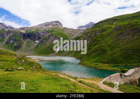 Lac bleu entre les pentes de montagne couvertes d'herbe verte. Grossglockner Hochalpenstrasse, Autriche. Banque D'Images