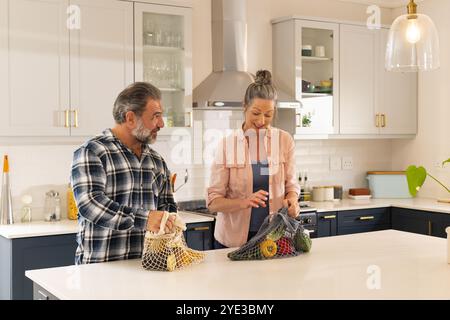 Couple mûr déballer l'épicerie dans la cuisine moderne, profiter du temps ensemble, à la maison Banque D'Images