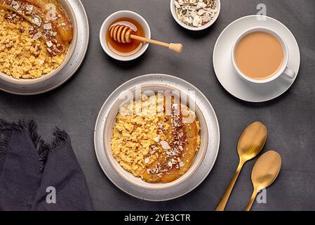 Photographie alimentaire de bouillie de millet avec banane caramélisée, noix de pécan, noix, flocons de noix de coco, chia, graines de lin, miel, thé au lait d'amande Banque D'Images