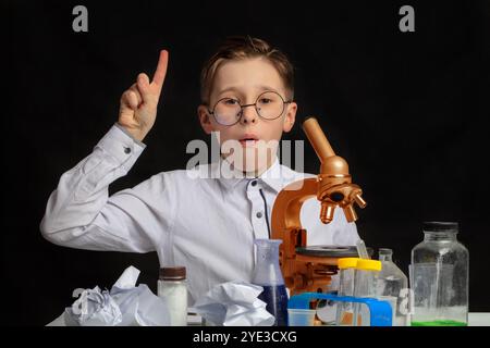 Une découverte intéressante a été faite par un petit scientifique portant des lunettes qui étudiait au microscope. Un chimiste garçon mignon est soudainement apparu avec Wit Banque D'Images