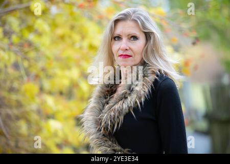 Une belle femme âgée blonde sur le fond d'un parc d'automne. Une femme adulte de cinquante ans. Banque D'Images