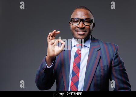 bel homme d'affaires africain confiant montrant le signe ok, sur fond gris, concept d'affaires réussies Banque D'Images