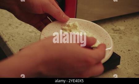 Il y a une gaufre préparée sur une assiette et un jeune cuisinier termine la préparation du plat fini. La cuisine d'un petit café confortable. Banque D'Images