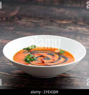 Une assiette de soupe de tomates maison avec fond de bois rustique basilic Banque D'Images