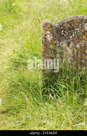 Gros plan d'une vieille pierre tombale oubliée dans un cimetière envahi par la végétation, Angleterre, Royaume-Uni Banque D'Images