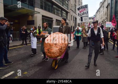 Londres, Royaume-Uni. 29 octobre 2024. Les activistes de la rébellion d'extinction marchent avec une pomme de terre modèle géante, « la dernière pomme de terre du monde », lors du deuxième jour de leur manifestation de trois jours sur le thème de la faim, appelant les compagnies d'assurance à cesser d'assurer les projets de combustibles fossiles. Crédit : Vuk Valcic/Alamy Live News Banque D'Images