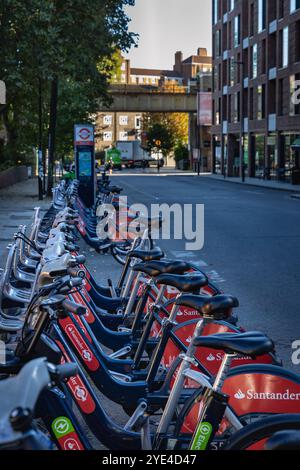 Longue rangée de vélos Santander rouges et bleus sur Castlehaven Road à Camden Town, Londres. Banque D'Images
