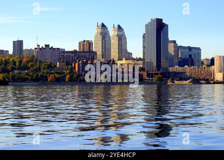 Grande ville sur Banks large rivière. Ville ukrainienne Dnipro, Ukraine. Belles tours modernes, bâtiments, gratte-ciel se reflètent dans l'eau matin, rivière flo Banque D'Images