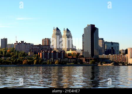 Grande ville sur Banks large rivière. Ville ukrainienne Dnipro, Ukraine. Belles tours modernes, bâtiments, gratte-ciel se reflètent dans l'eau matin, rivière flo Banque D'Images