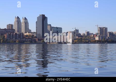 Grande ville sur Banks large rivière. Ville ukrainienne Dnipro, Ukraine. Belles tours modernes, bâtiments, gratte-ciel se reflètent dans l'eau matin, rivière flo Banque D'Images