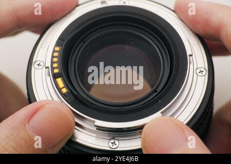 Un homme tenant un vieil objectif d'appareil photo avec de la poussière dans ses mains. Banque D'Images