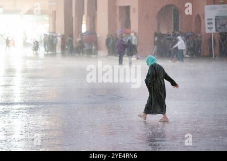 Marrakech, Maroc Une femme humide trempée traverse Jemaa el-Fnaa, la place principale de la vieille ville de la médina de Marrakech pendant un orage et de fortes pluies Banque D'Images