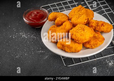 Nuggets de poulet frits dorés traditionnels sur une assiette, avec sauce ketchup. Banque D'Images