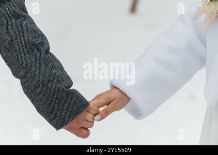 Moment tendre : mains d'amour entrelacées dans un pays des merveilles hivernales. Banque D'Images